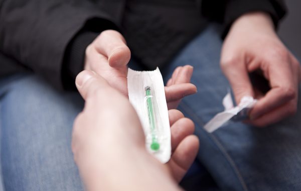 A drug worker giving a service user clean hypodermic needles and syringes