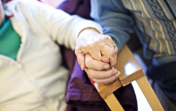 An elderly couple hold hands