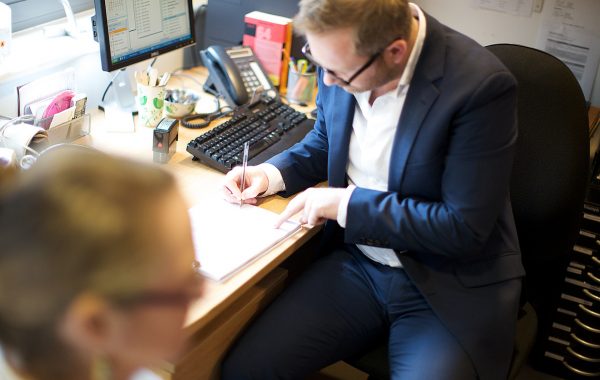 A GP writes notes during a consultation with a patient
