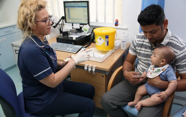A primary care nurse with a father and baby