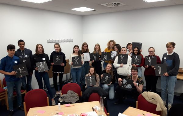 Young people holding up pictures of skeletons