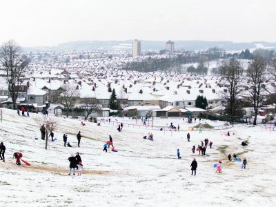 A snowy scene in Bristol, with families playing in a park