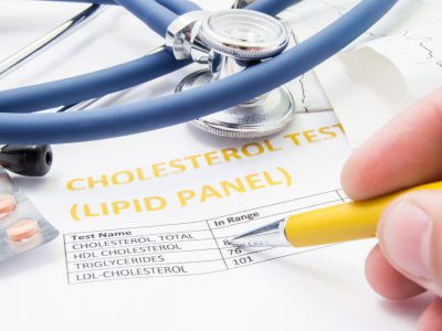 Statin pills and a stethoscope on a form about blood fat levels