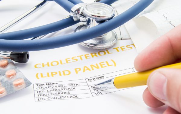 Statin pills and a stethoscope on a form about blood fat levels