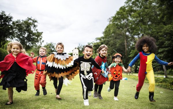Children in Halloween costumes running around outside