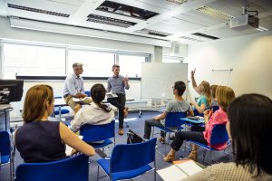 Group of people sitting in meeting room during workshop, listening to a presentation