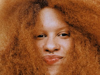A close up of a woman with a nose ring, surrounded by her hair
