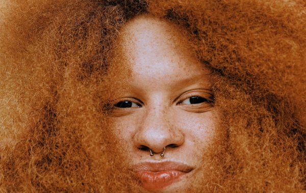 A close up of a woman with a nose ring, surrounded by her hair