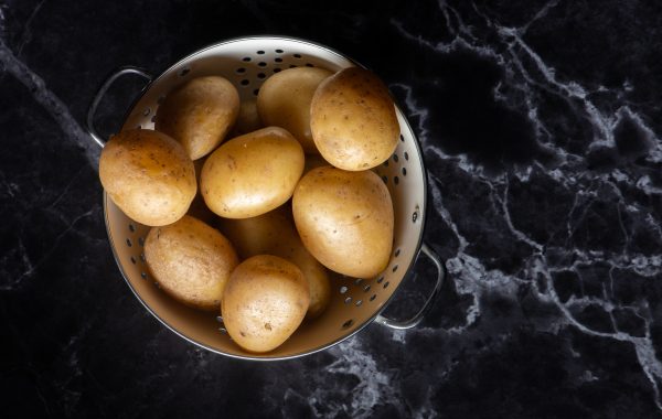 Potatoes in a colander on a marble worktop