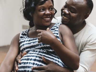 A Black pregnant woman laughs with her partner