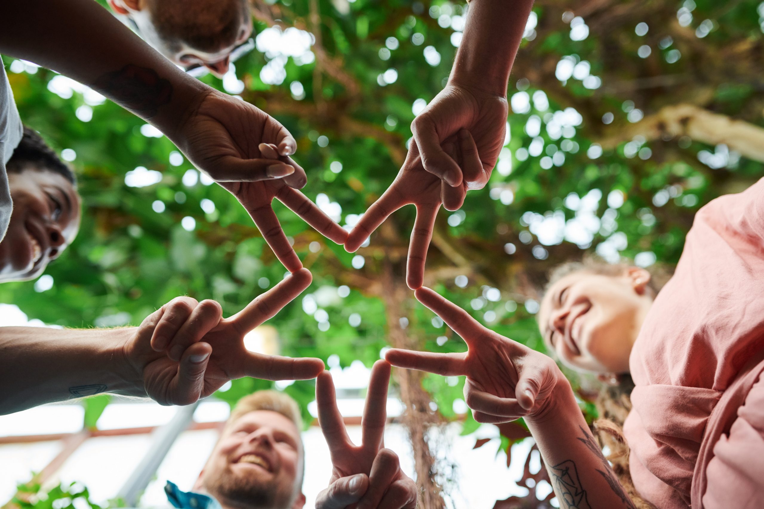 A group of children is holding their hands together in the victory sign