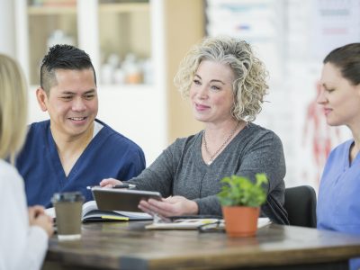 Four healthcare professionals are sitting at a table while deep in conversation