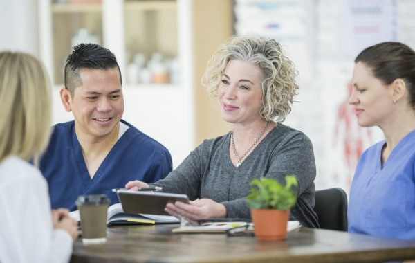 Four healthcare professionals are sitting at a table while deep in conversation