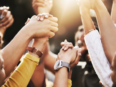 A group of women clasp hands in solidarity and celebration