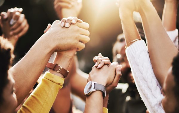 A group of women clasp hands in solidarity and celebration