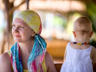 A mother wearing a headscarf is sitting on a bench enjoying a moment with her young daughter