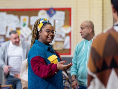 A woman welcomes people to a community group meeting