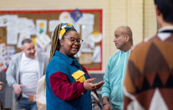 A woman welcomes people to a community group meeting