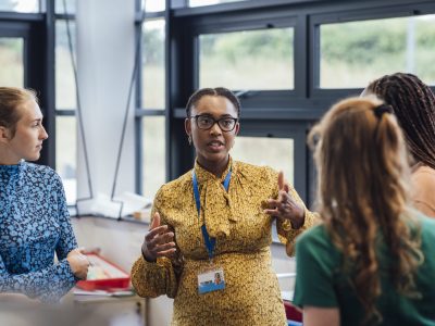 A worker wearing a lanyard in discussion with colleagues