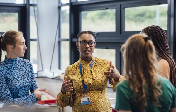 A worker wearing a lanyard in discussion with colleagues
