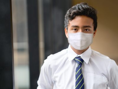 A pupil in school uniform wears a face covering