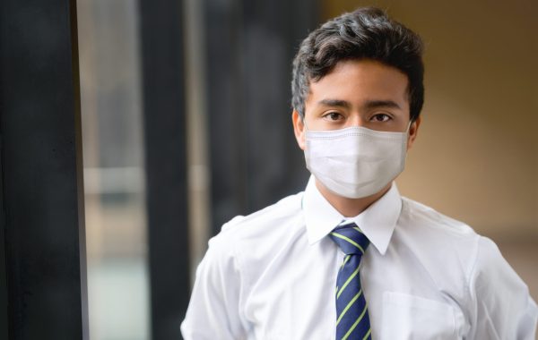 A pupil in school uniform wears a face covering
